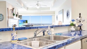 A kitchen with a large window, a ceiling fan, and a view of the ocean. - Upscale Condo, Amazing Views, Pools and Pickleball (Lake Ozark)