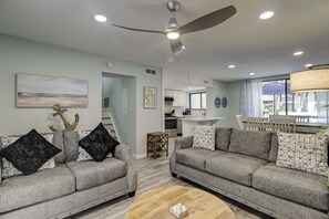 Uma sala de estar moderna com dois sofás cinzas, uma mesa de centro de madeira e um ventilador de teto.