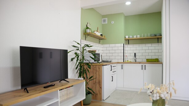Eine moderne Küche mit weißen Schränken, einer Holzarbeitsplatte und einer grünen Spritzschutzwand.