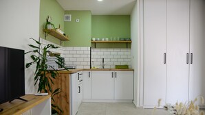 Eine moderne Küche mit weißen Schränken, einer Holz Arbeitsplatte und einer grünen Wand.