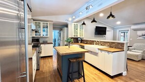 Una cocina moderna con una isla central, suelo de madera e iluminación colgante.
