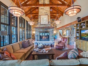 A spacious living room with a stone fireplace, large windows, and a cozy seating area.