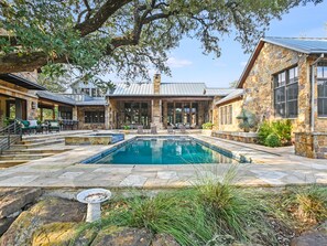 A stone building with a swimming pool, outdoor seating, and a covered patio area.
