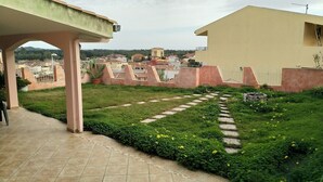 A rooftop garden with a paved walkway, green hedges, and yellow flowers. - Panorama Apartment (Intimate, up to 3 people) (Muravera)
