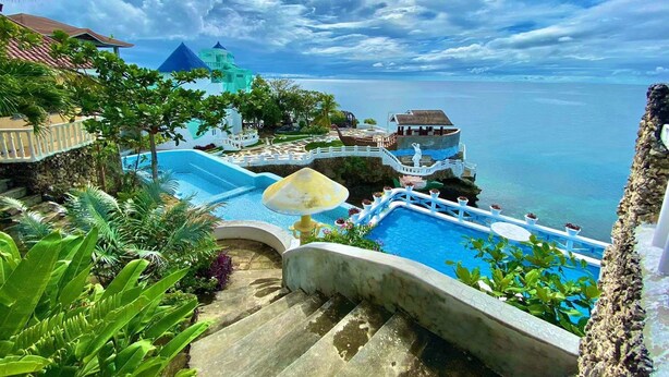A resort with a swimming pool, a staircase, and a view of the ocean. - azure camotes resort hotel (San Francisco)