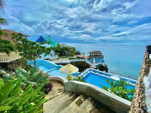 A resort with a swimming pool, a staircase, and a view of the ocean. - azure camotes resort hotel (San Francisco)