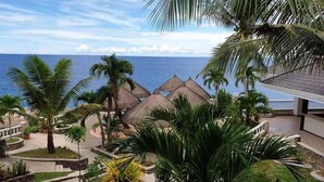 A resort with thatched-roof structures, palm trees, and a view of the ocean. - azure camotes resort hotel (San Francisco)