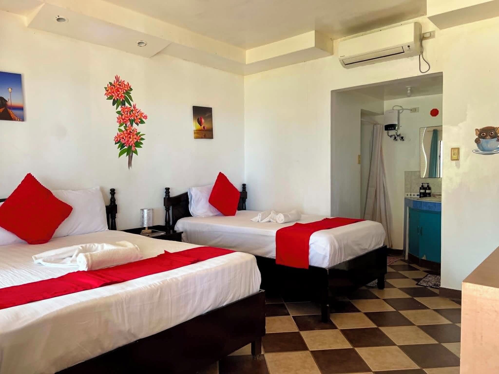 A hotel room with two beds, a checkered floor, a shower area, and a painting on the wall.