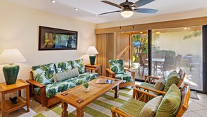 A living room with a sofa, armchairs, a coffee table, and a ceiling fan.