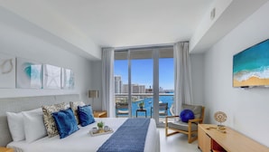 Camera d'hotel moderna con un letto grande, una scrivania, una sedia e vista sulla città attraverso una grande finestra.