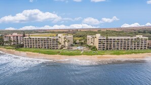 Un hotel frente al mar con varias construcciones, un área de piscina y la playa.