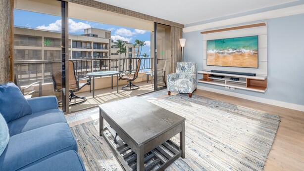 Una sala de estar moderna con sofá, mesa de centro, televisor y balcón con mobiliario exterior.