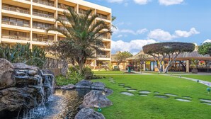 Un hotel con piscina, palmeras y un césped bien cuidado.