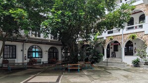 An outdoor courtyard with benches, a large tree, and a building with arched windows and a stone facade. - w* | Bright Loft in Santa Ana w/ AC (Panamá)