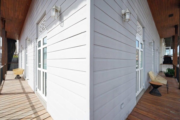 Una casa de madera blanca con un porche cubierto, una silla amarilla y una pequeña mesa.