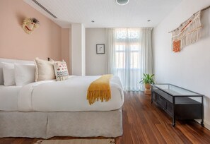 Un dormitorio con cama, mesita de noche y una planta en maceta.