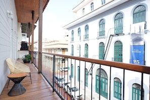 A balcony with a wooden floor, a wicker chair, and a potted plant.