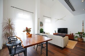 Un salon moderne comprenant un coin repas, un canapé, un téléviseur et une grande plante.