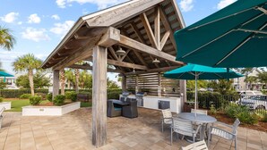 Un patio al aire libre con una pérgola de madera, cocina exterior y zona de estar.