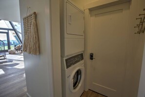Ein Waschraum mit Waschmaschine und Trockner, einer Tür mit Griff sowie einem an der Wand befestigten Handtuchhalter.