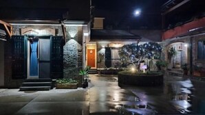 A nighttime view of a building with a stone facade, a blue door, and a small garden area with a fountain. - Midway House Apartment with free internal parking (Sant'Egidio del Monte Albino)
