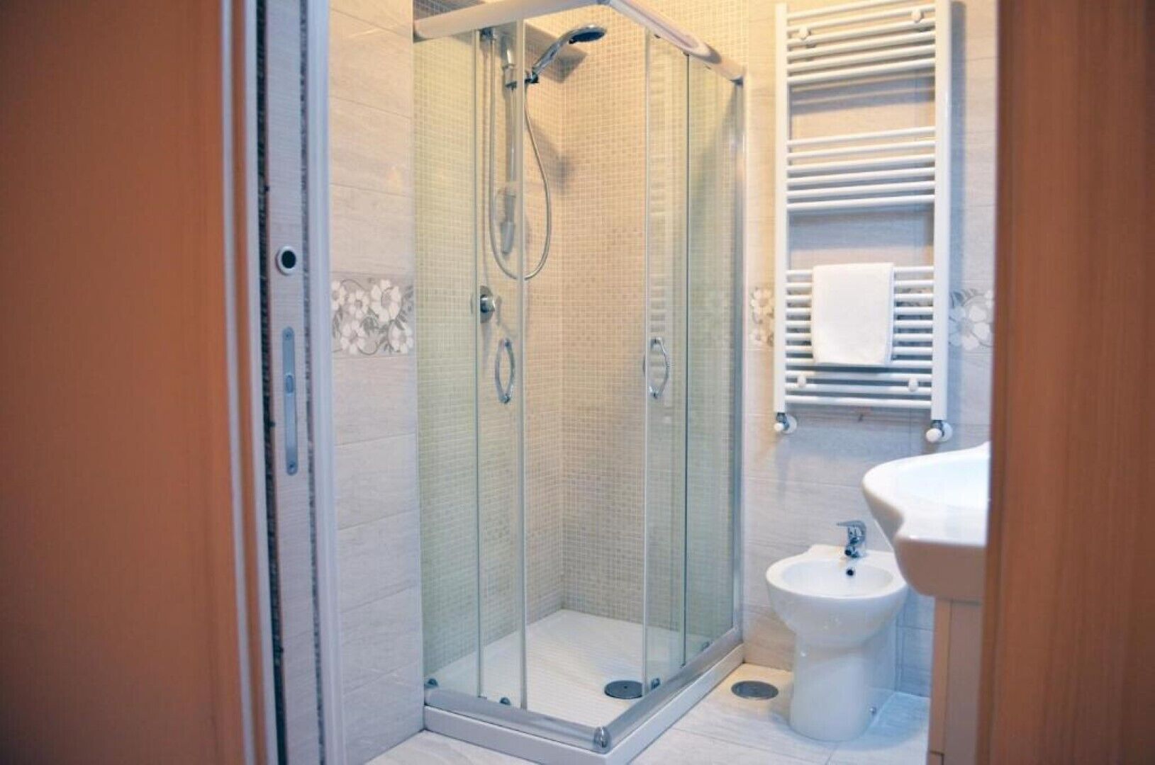 Une salle de bain moderne avec une douche à parois de verre, un lavabo blanc et un porte-serviettes.
