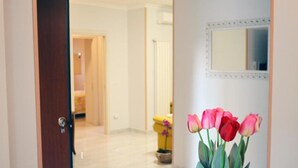A hallway with a wooden door, a mirror, and a vase of pink tulips. - Midway House Apartment with free internal parking (Sant'Egidio del Monte Albino)