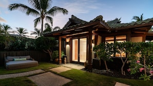A house with a covered patio, a wooden fence, and a small garden with a bench and potted plants. - Beach Walker: Exclusive w/ Pool,Views,Mauna Lani Beach,Golf/Pickleball (Kamuela)