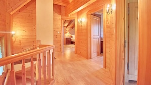 A wooden interior with a staircase, a hallway, and a bedroom with a bed and nightstand. - Family chalet overlooking the Midi Teeth (Champéry)