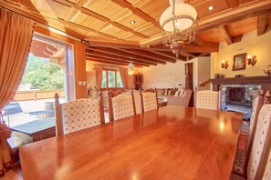 A spacious dining area with a large wooden table and patterned upholstered chairs.