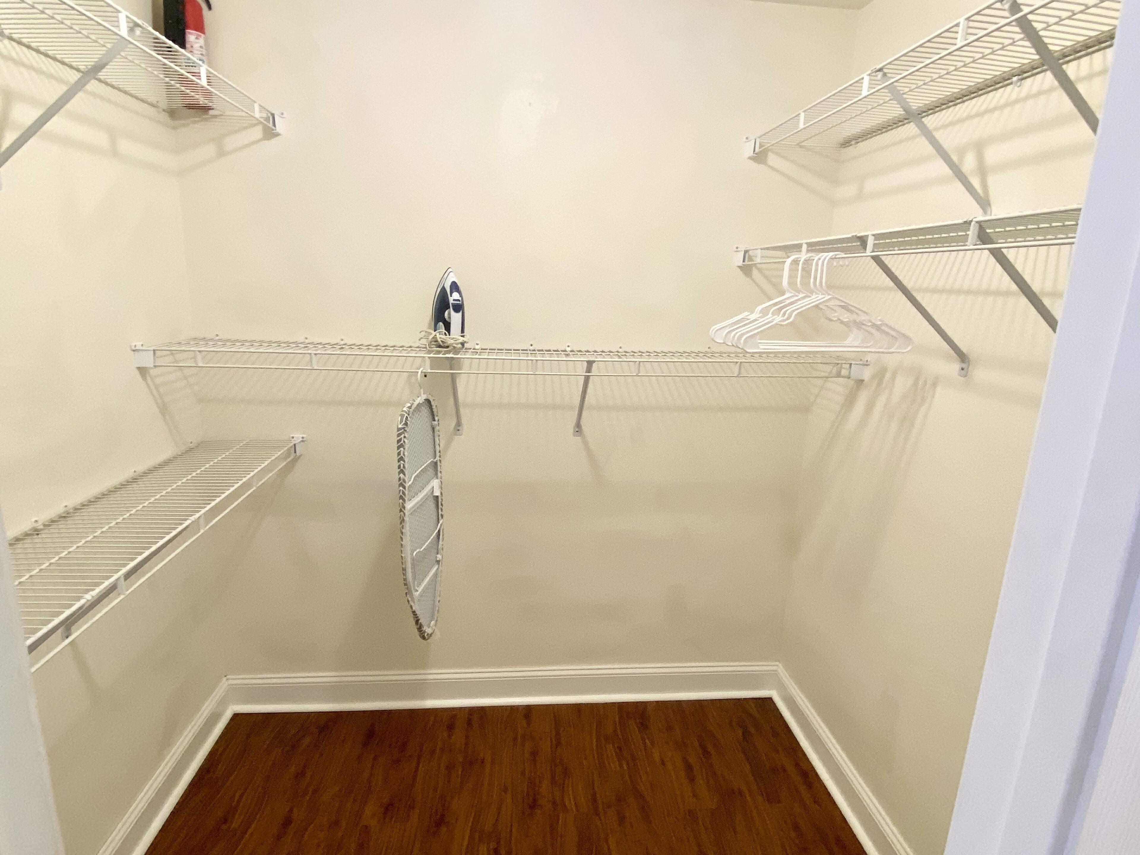 Un vestidor con estanterías metálicas y suelo de madera.