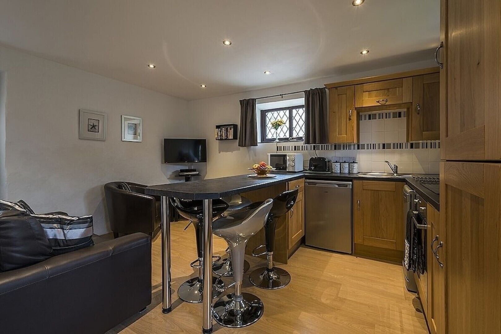 A compact kitchen with a central island, wooden cabinets, and modern appliances.