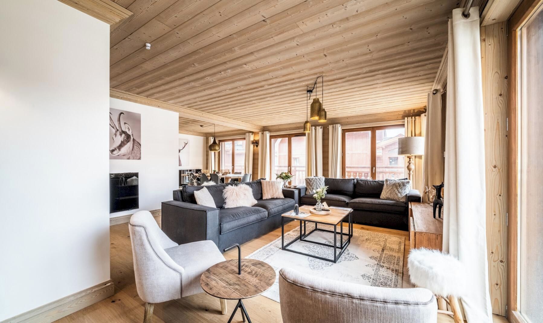 A spacious living area with a wooden ceiling, a sofa set, a coffee table, and a fireplace.