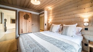 Ein Schlafzimmer mit Holzboden, einem großen Bett mit gestreifter Decke und zwei Nachttischlampen.