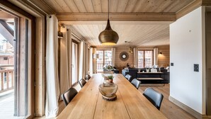 Ein geräumiger Essbereich mit einem langen Holztisch, umgeben von Stühlen und einer hängenden Pendelleuchte.