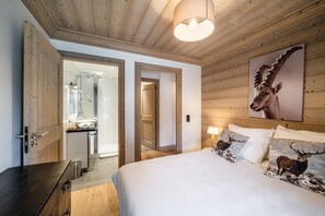 A bedroom with a wooden ceiling, a bed with white bedding, a large mirror, and a wall-mounted lamp.