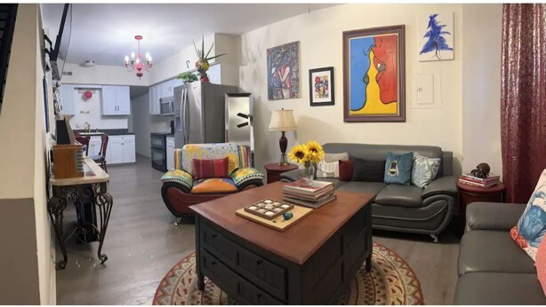 A living room with a sofa, a coffee table, and a dining area with a chandelier. - The Most Colorful Home in Atlantic City (Atlantic City)