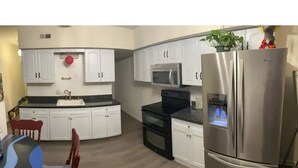 A modern kitchen with white cabinets, a stainless steel refrigerator, a microwave, and a built-in oven. - The Most Colorful Home in Atlantic City (Atlantic City)