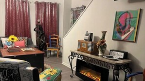 A cozy living room with a fireplace, a sofa, a coffee table, and a bookshelf. - The Most Colorful Home in Atlantic City (Atlantic City)