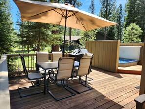 En utomhusveranda med ett bord och stolar, en överbyggd grillplats och en bubbelpool.