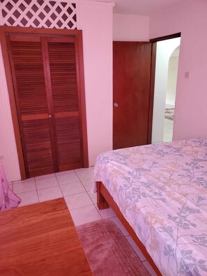 Cozy retreat with a floral-patterned bedspread, a wooden wardrobe, and a small table.