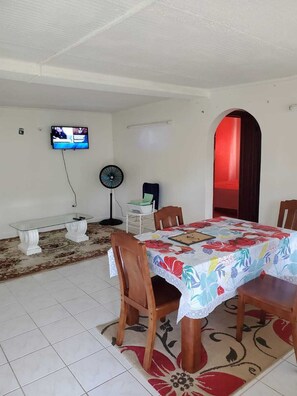 Enjoy meals in this dining area with a table, flat-screen TV, and standing fan.