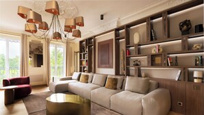 A modern living room with a sectional sofa, a round coffee table, and a built-in bookshelf. - Merveil - Luxury Suite - Marais - Ponceau (Paris)