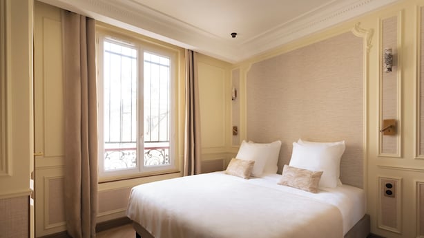 Una habitación de hotel con una cama grande, una ventana con cortinas y una puerta.