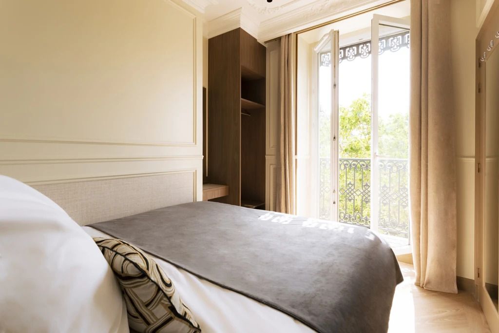 A hotel room with a bed, a wardrobe, and a balcony with a view.