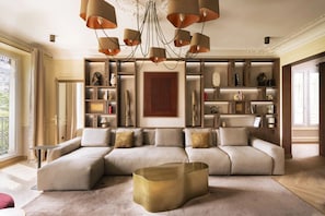 A modern living room with a sectional sofa, a unique gold coffee table, and a contemporary chandelier. - Merveil - Luxury Suite - Marais - Ponceau (Paris)