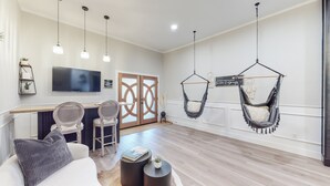 Una sala de estar moderna con sofá, sillas, una mesa de centro, televisor y dos hamacas colgantes.