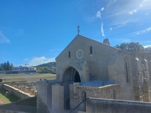 A historical stone building with a prominent archway and a cross on top, likely a church or cathedral, with surrounding ruins and a clear sky. - HOLIDAY HOUSE 15 MINUTES FROM THE BEACH (1st FLOOR) (AMIEIRO)