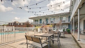 An outdoor patio with a pool, seating, and a building with a balcony. - Melrose Studio - Pool & Free Parking Near Downtown (Nashville)