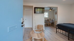 A bedroom with a bed, a small round table with a basket, a chair, and a TV mounted on the wall. - Melrose Studio - Pool & Free Parking Near Downtown (Nashville)